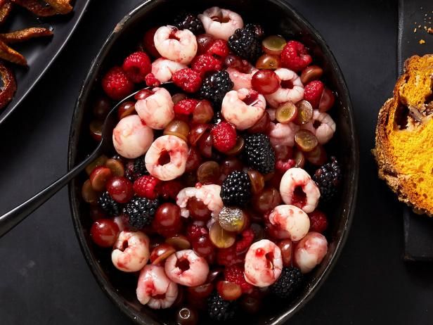 a bowl filled with fruit next to some other foods on top of a black table