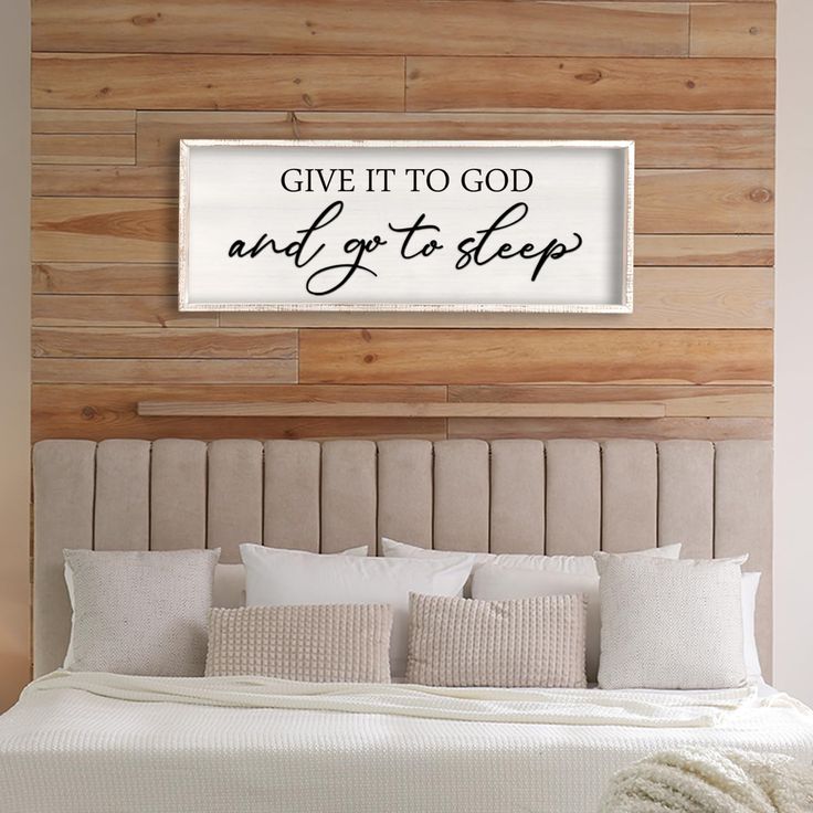 a bed with white pillows and a wooden headboard that says give it to god and go to sleep