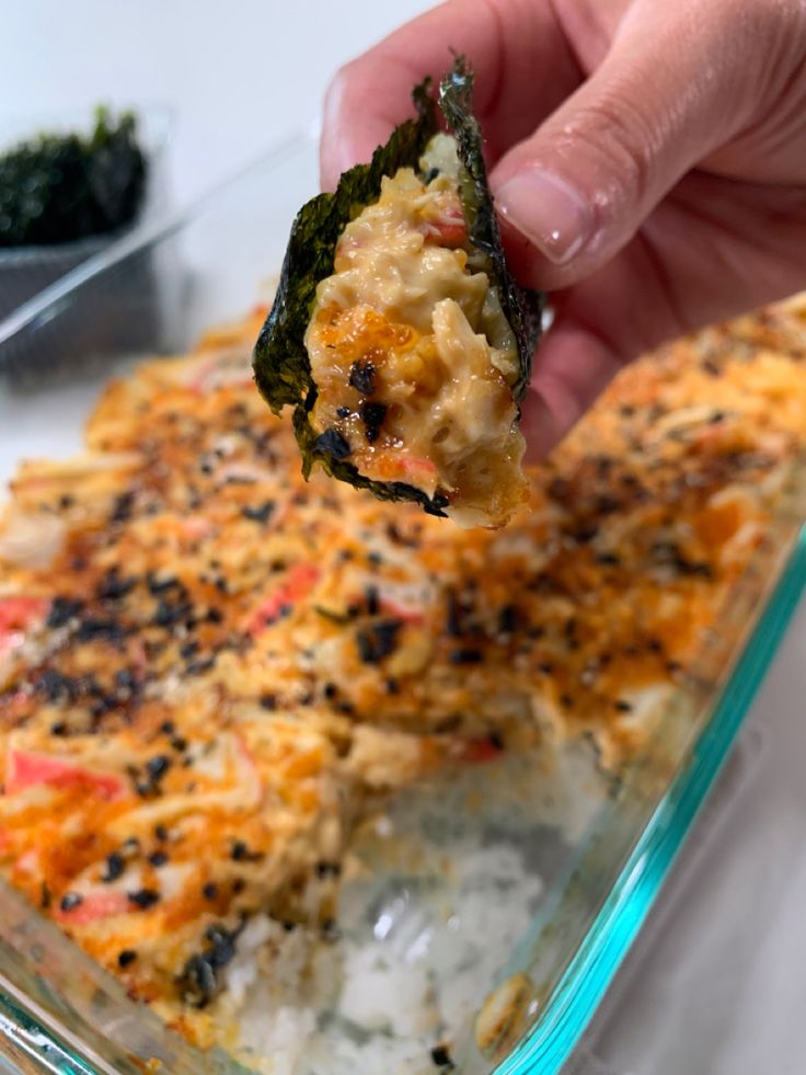 a hand holding up a piece of broccoli casserole with rice and cheese