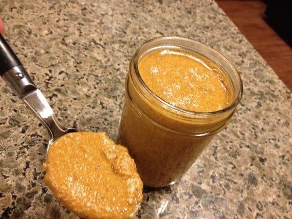 a jar of peanut butter next to a cookie on a counter top with a spoon