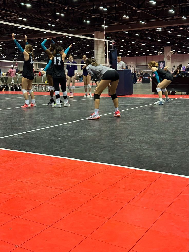 the women are playing volleyball on the court with their hands in the air as people watch