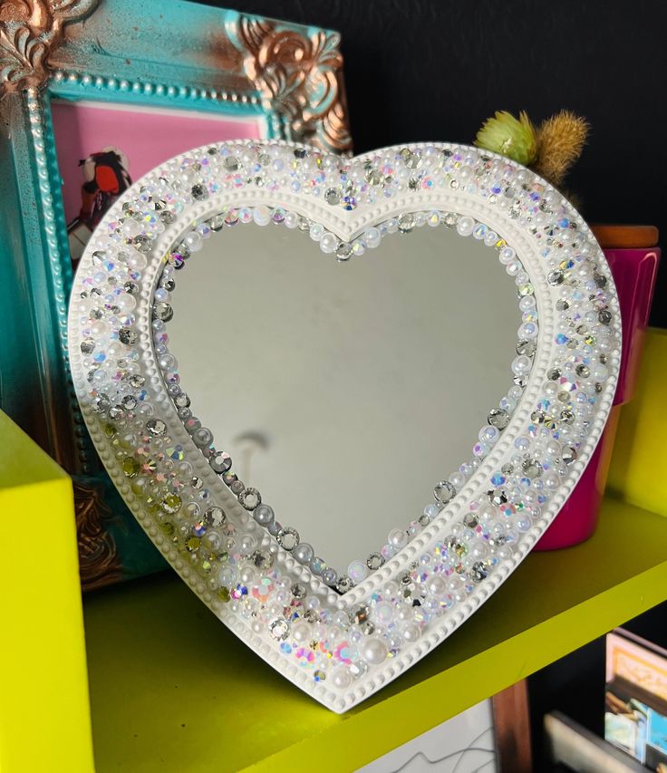 a heart shaped mirror sitting on top of a green shelf