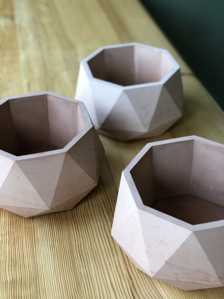 three white vases sitting on top of a wooden table