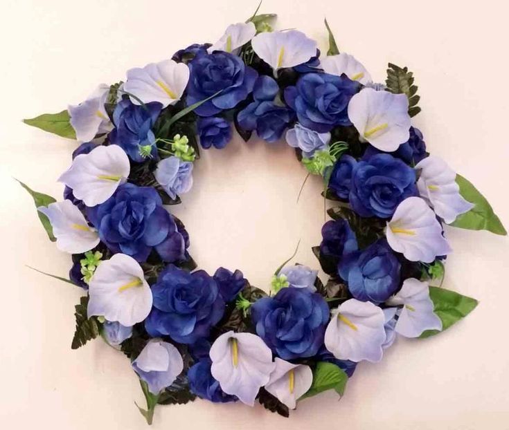 blue and white flowers are arranged in a circle on the wall, ready to be used as a wreath