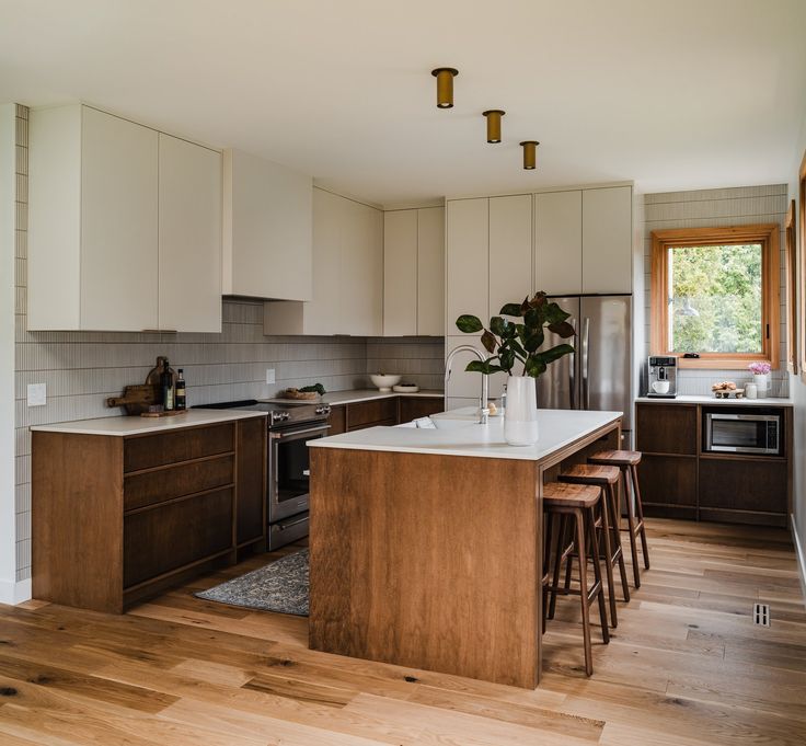 a kitchen with wooden flooring and white counter tops next to an island in the middle