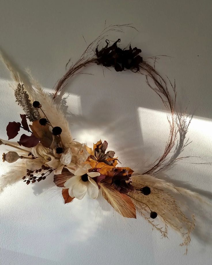 an arrangement of dried flowers and leaves on a white surface