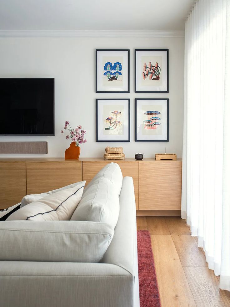 a living room with pictures on the wall and a couch in front of a flat screen tv