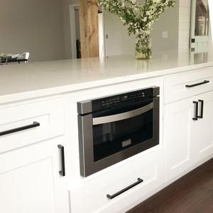 a modern kitchen with white cabinets and stainless steel appliances, including a built - in oven