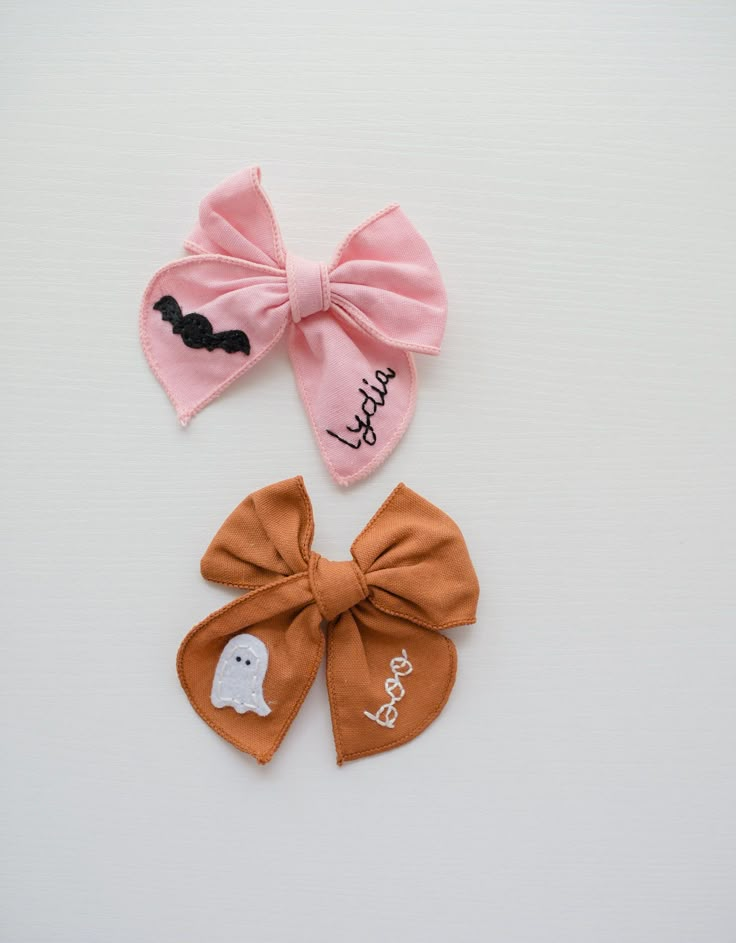 two hair bows with ghost on them sitting next to each other in front of a white background