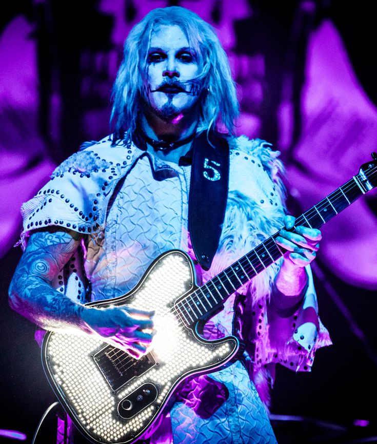 a man with blue hair holding a guitar