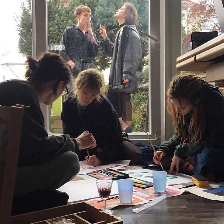 several people are sitting at a table doing art