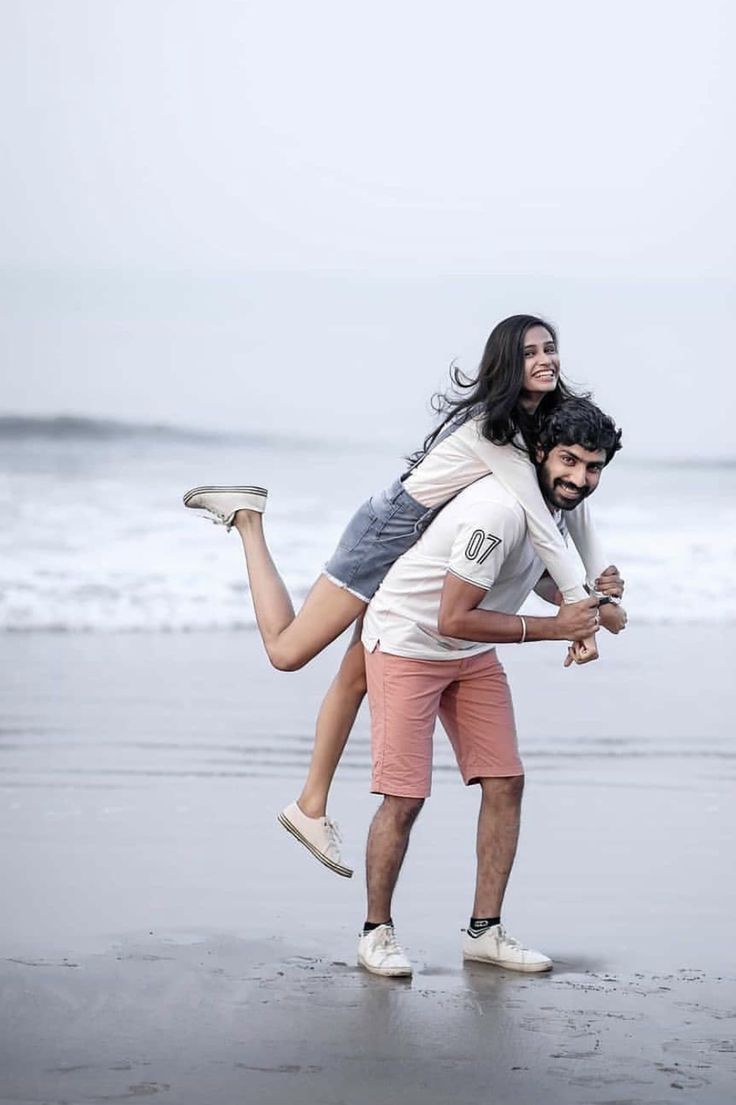 a man carrying a woman on his back at the beach