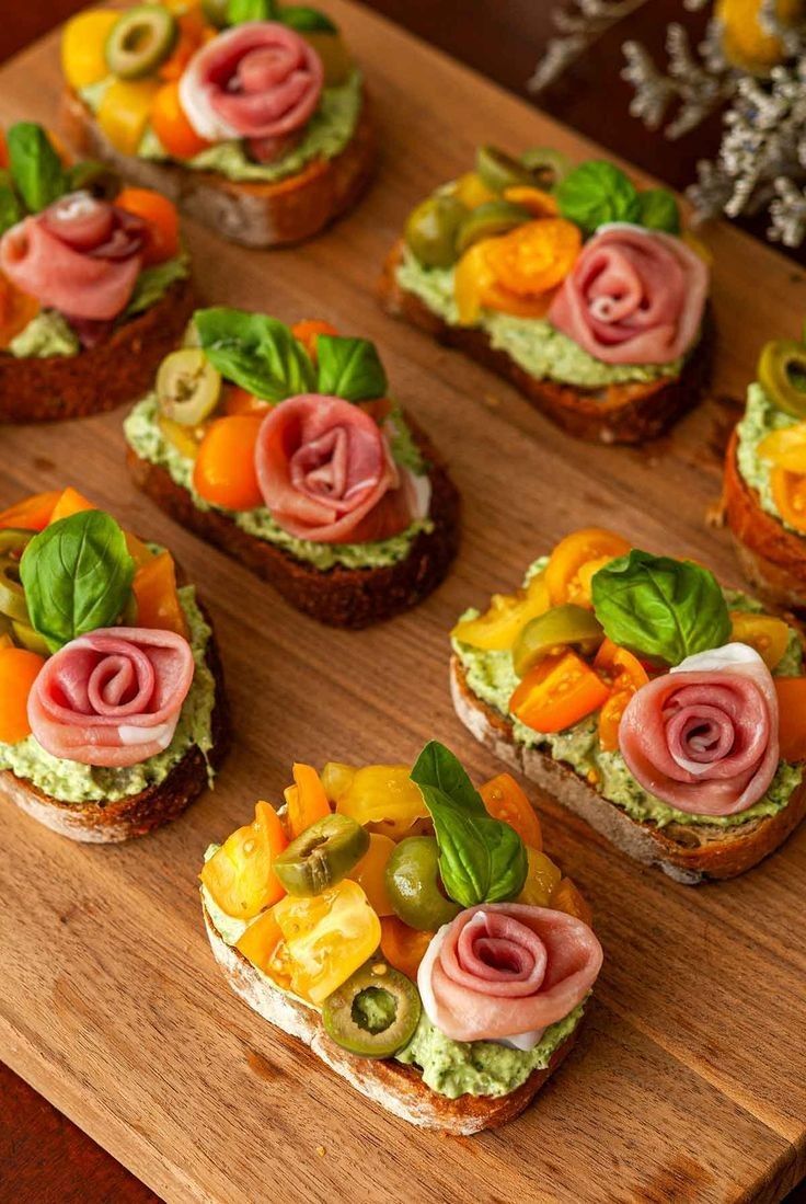 many small sandwiches with different toppings on them sitting on a cutting board next to flowers