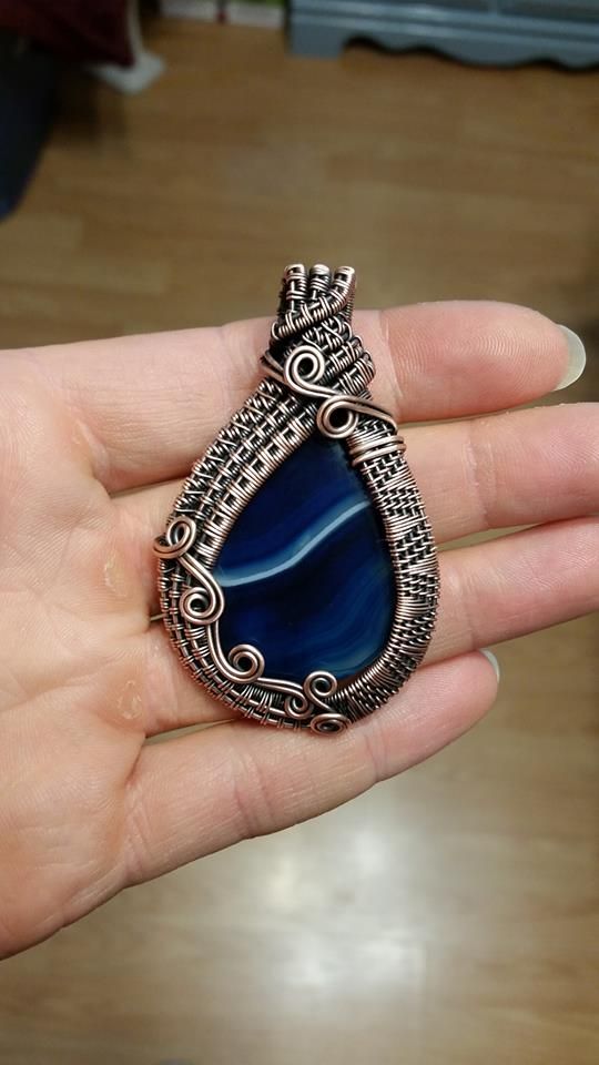 a person is holding a blue stone in their hand and it looks like they are wearing a necklace