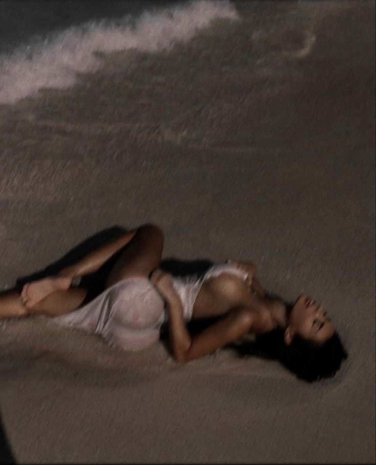 a woman laying on the beach with her head down