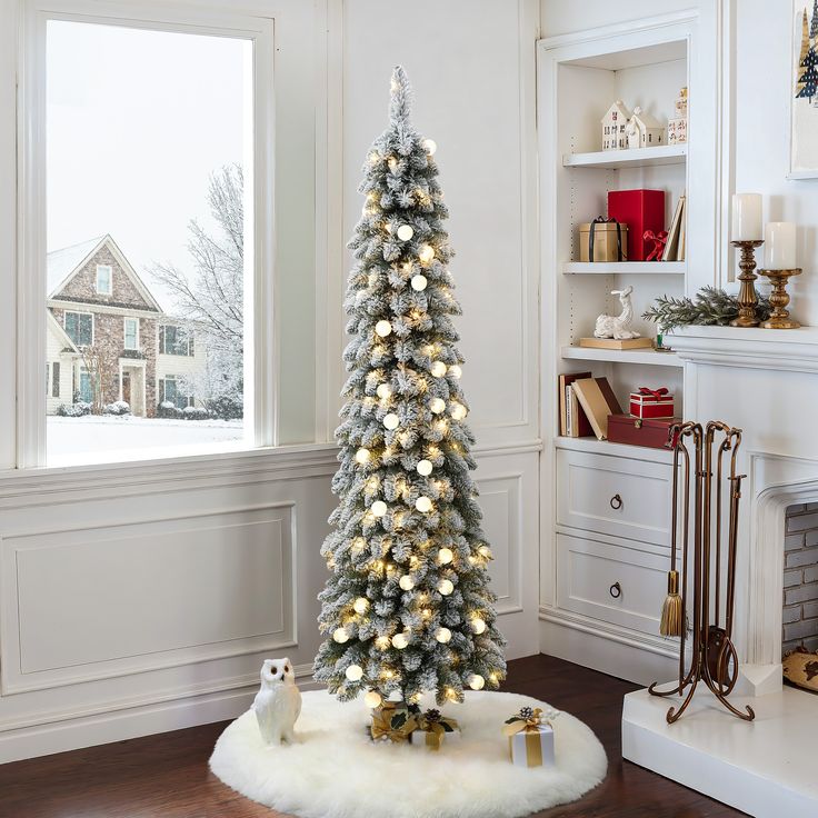 a decorated christmas tree in front of a window with white and silver decorations on it