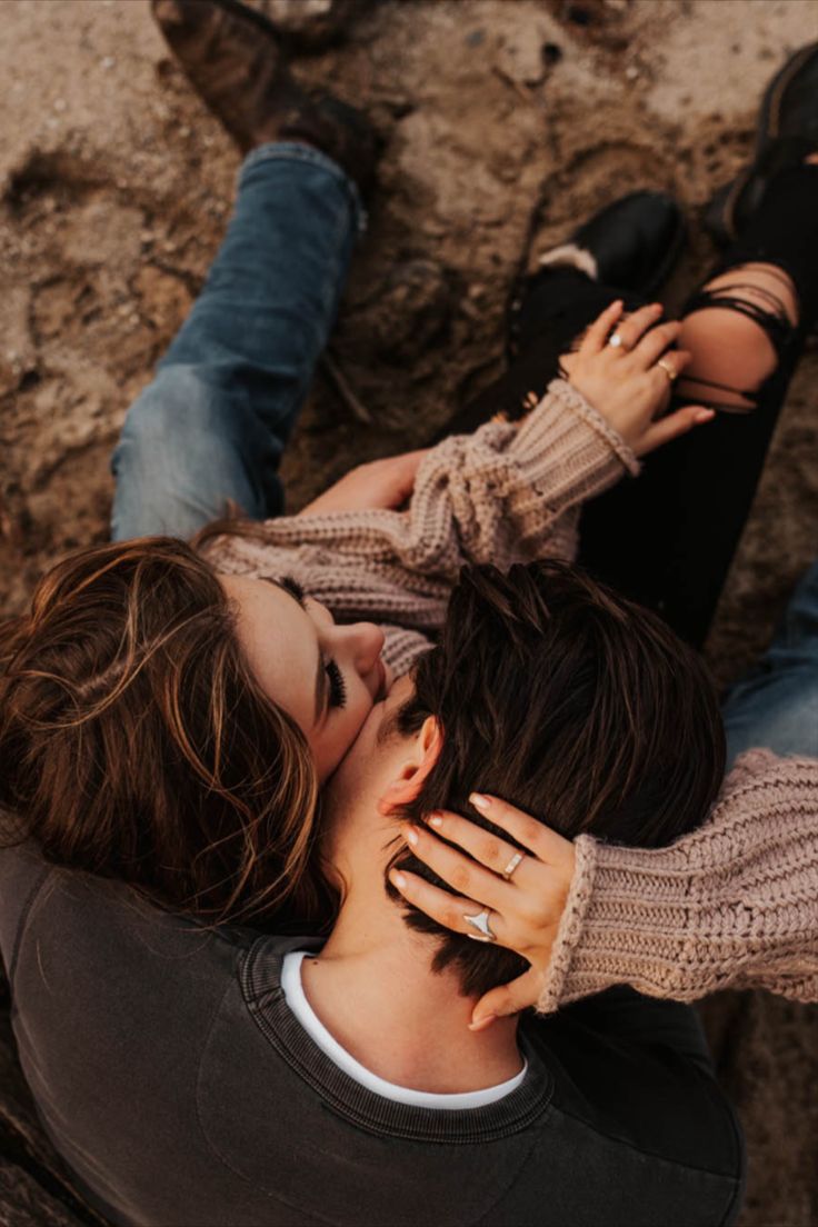 two people laying on the ground next to each other with their hands around one another