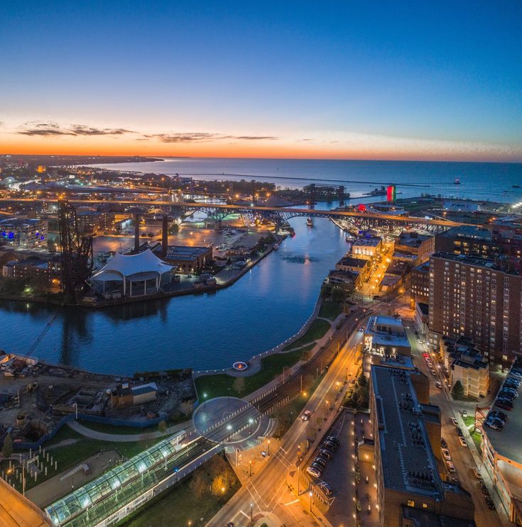 an aerial view of a city and the ocean at night with bright lights in the foreground