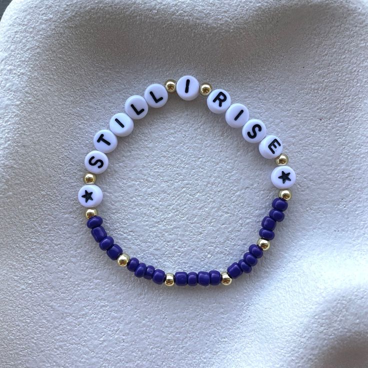 a beaded bracelet with the word jesus on it and two beads in gold, white and blue