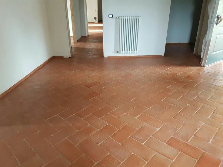 an empty room with brick flooring and white walls on either side of the door