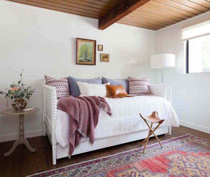 a white bed sitting in a bedroom on top of a wooden floor