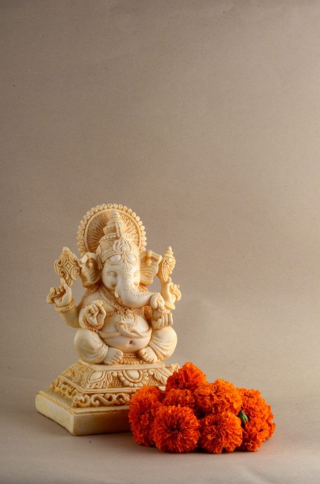 there is an orange flower next to the small statue and it looks like ganesh