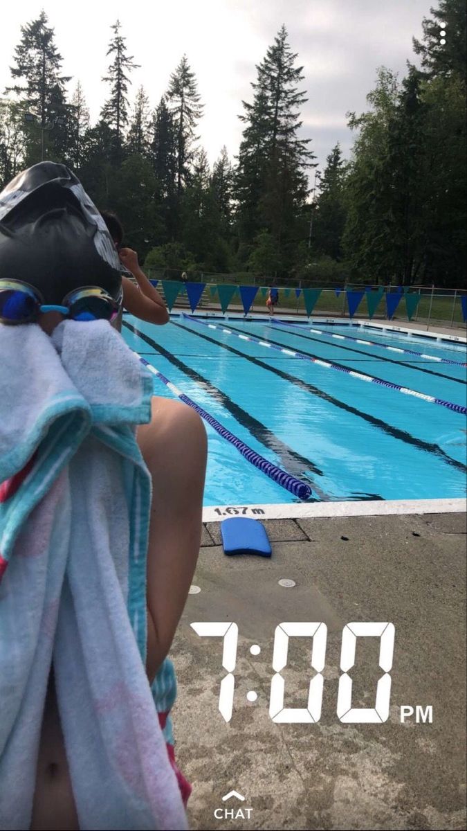 a person sitting in front of a swimming pool with a towel over their head and a helmet on his head