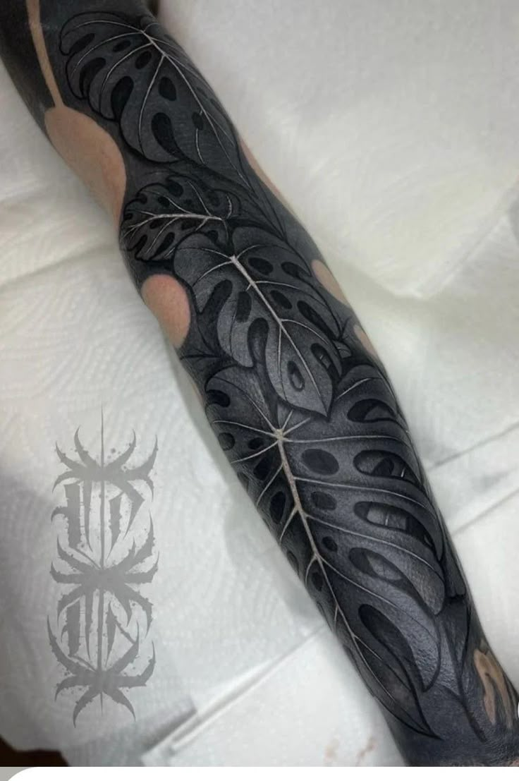 a man's arm covered in black ink with an intricate design on it,