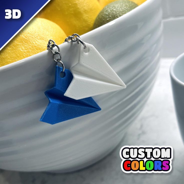 a white bowl filled with lemons and oranges next to a blue origami keychain