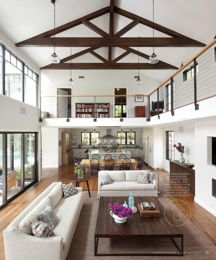 a living room filled with lots of furniture and wooden flooring next to tall windows