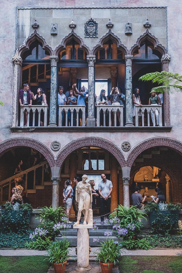 people standing on the balconies of a building with statues in front of them