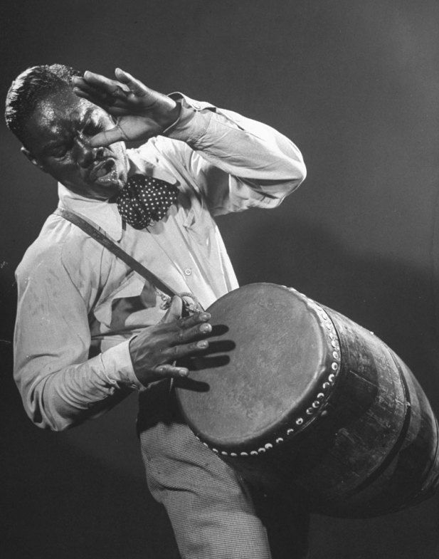 a man holding a large drum while wearing a bow tie