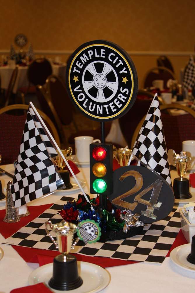 the table is decorated with black and white checkered tables cloths, gold trimmings, and an embellished sign that says temple city volunteers