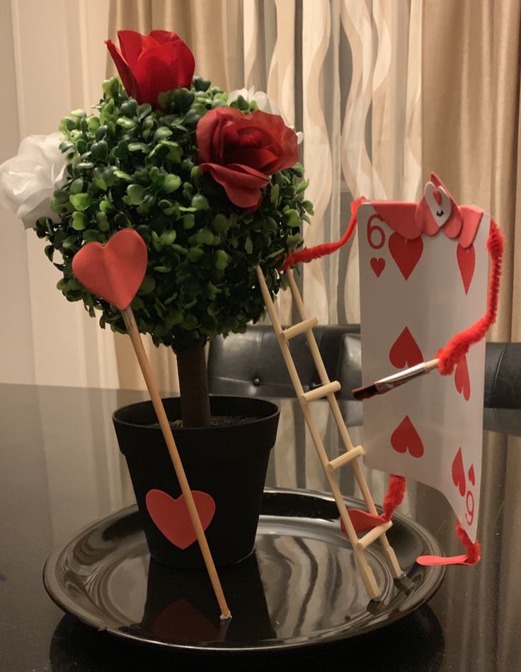 two vases with roses in them on a table next to a potted plant