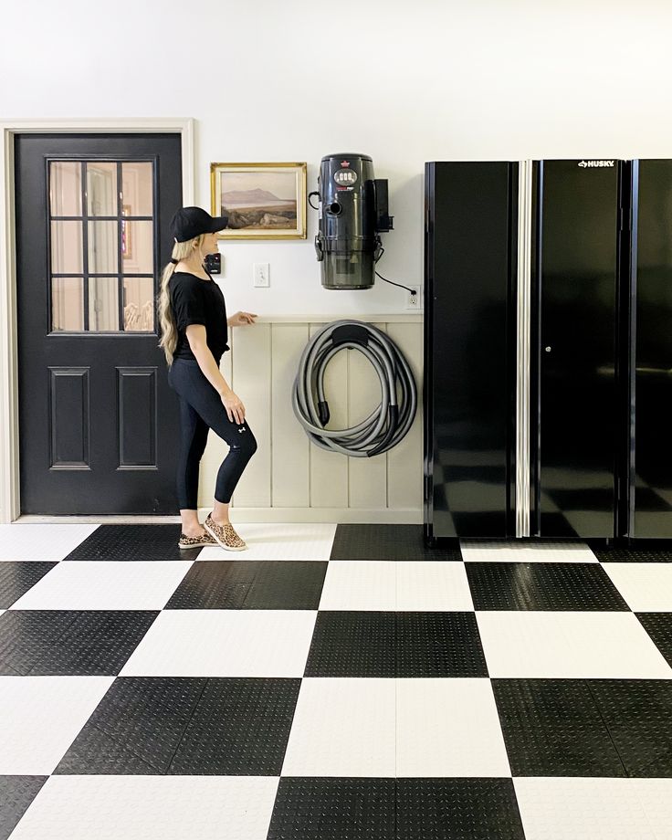 a woman standing in front of a black and white checkered floor with refrigerators