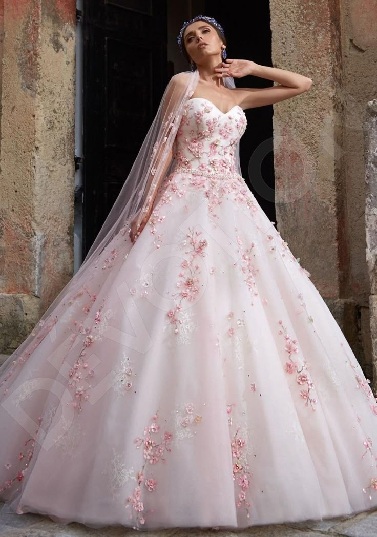 a woman in a pink wedding dress standing on a stone floor next to an old building