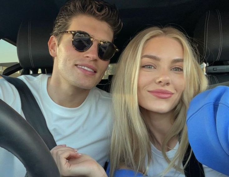 a man and woman sitting in the back seat of a car, smiling at the camera