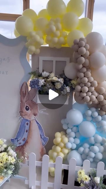 a table with balloons, flowers and an easter bunny sign on it's side