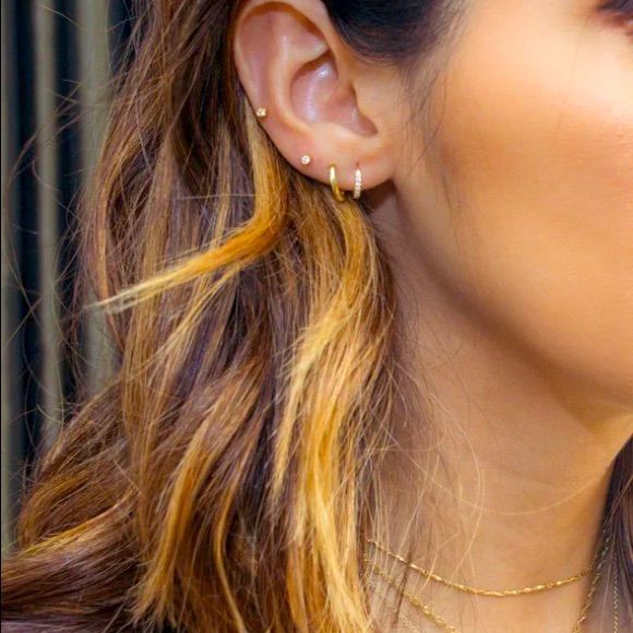 a close up of a person with ear piercings on their ears and wearing a necklace