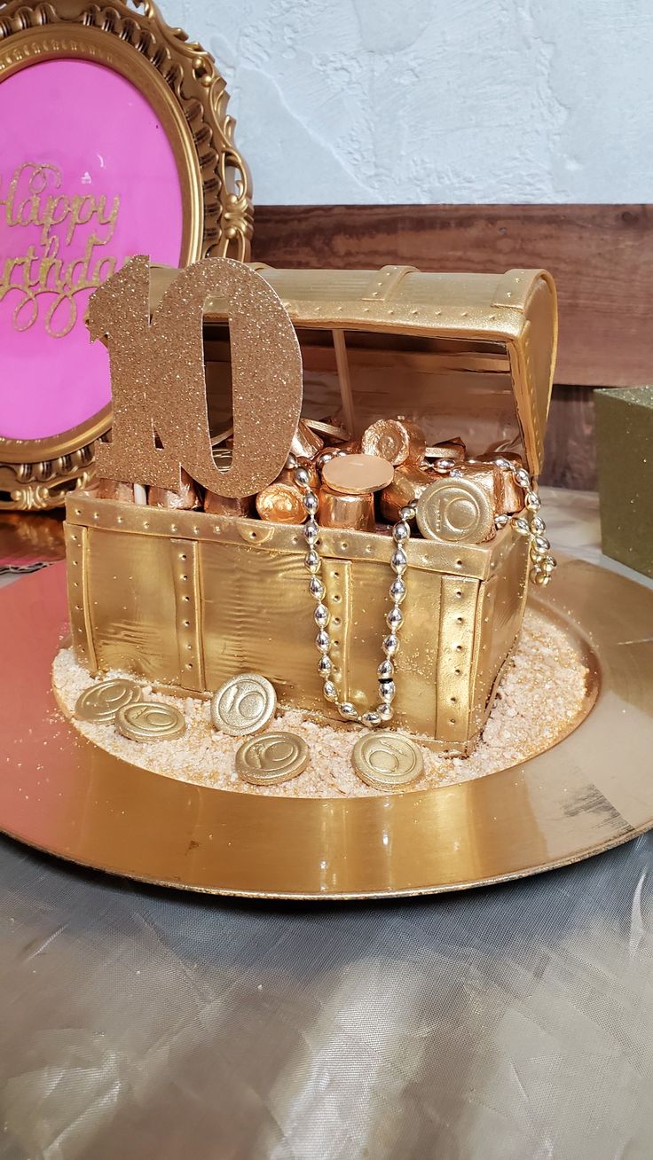 there is a cake that has been made to look like a trunk with gold decorations on it