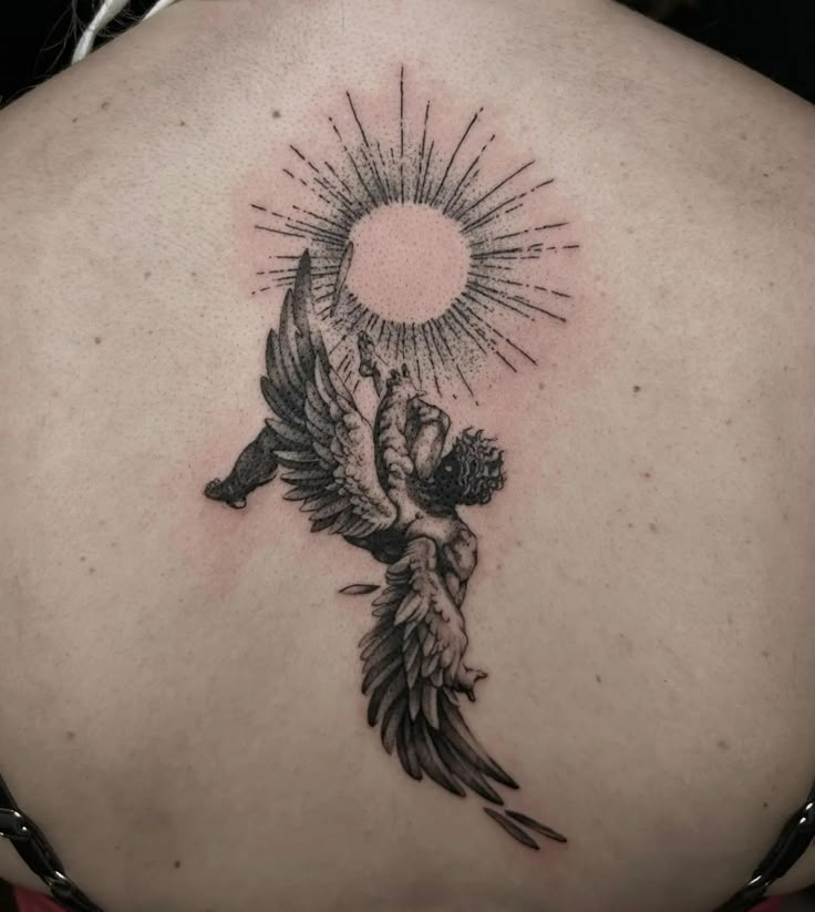 the back of a woman's shoulder with an angel and sun tattoo on it