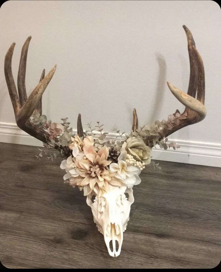 a deer skull with flowers on it's antlers is sitting on the floor