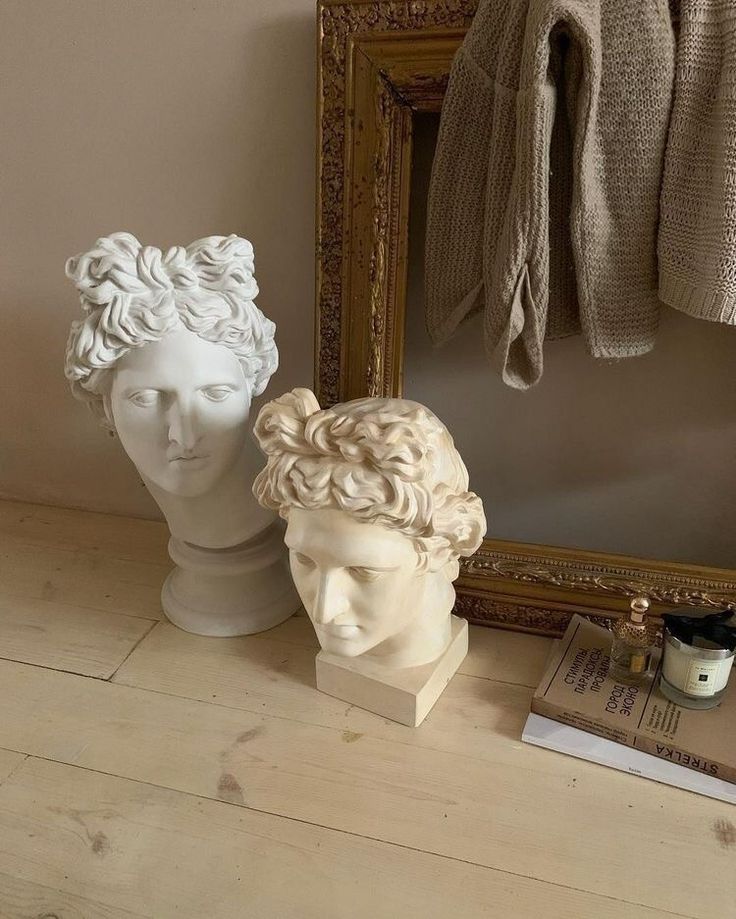 two busturines sitting next to a mirror on top of a wooden floor