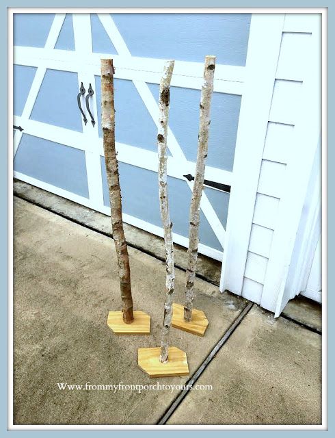 three small trees are standing in front of a garage door