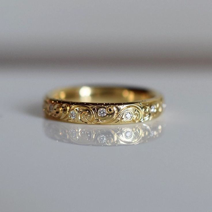 a gold wedding ring with three diamonds on it's side, sitting on a white surface