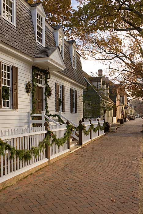 a street lined with white houses covered in christmas wreaths