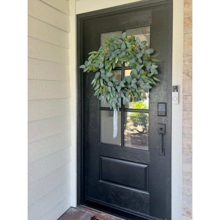 a black front door with a wreath on it