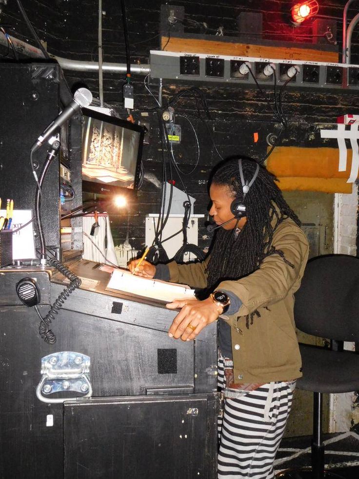 a woman wearing headphones writing on a piece of paper in front of a tv