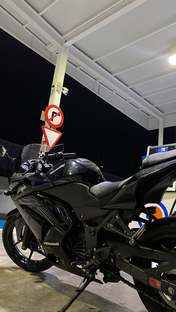 a black motorcycle parked in a garage next to a speed limit sign and street signs