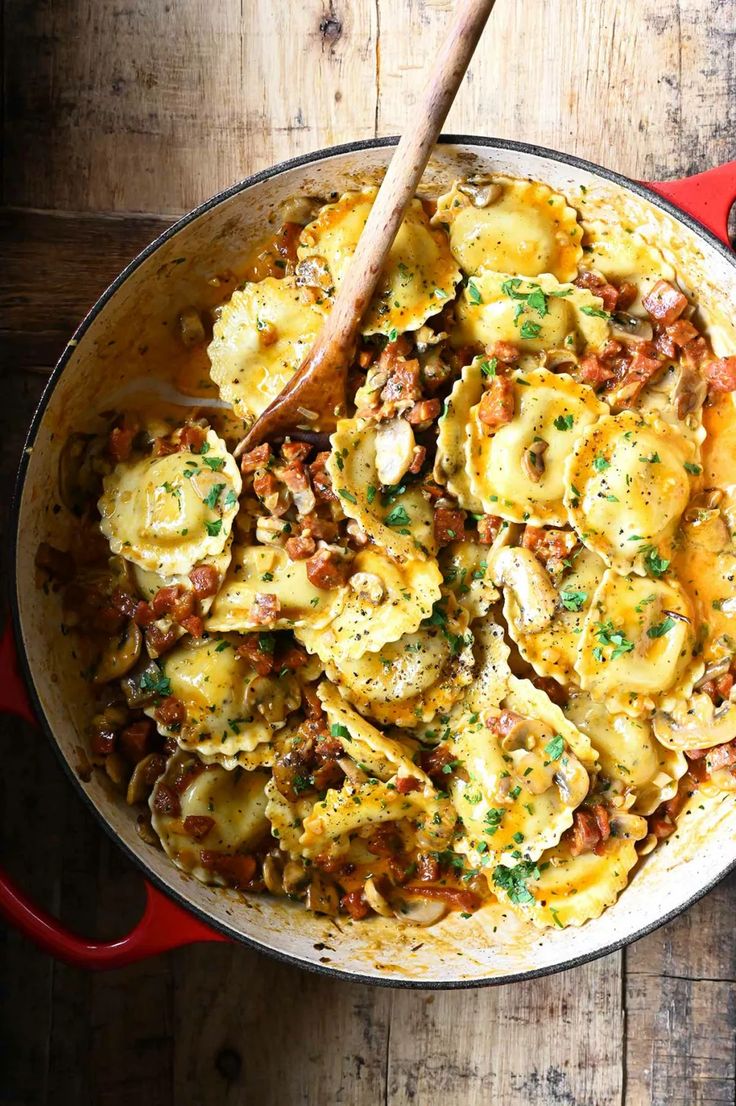 a pan filled with pasta and meat on top of a wooden table